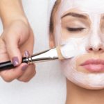 Woman receiving facial mask at beauty salon